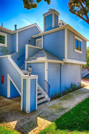 Front view of a two-story house with blue siding and external staircase.