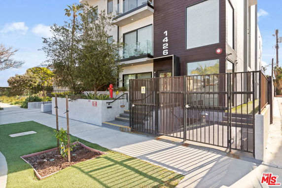 Front view of a modern multi-story building with gated entrance and landscaping.