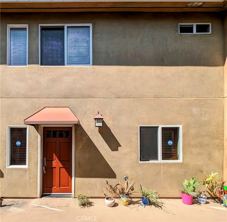 Front view of a house with a red door and tan exterior walls.