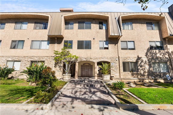 Front view of a multi-story residential building with a stone facade and multiple windows.