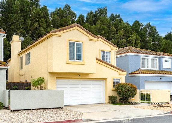 Front view of a two-story house with a white garage door and a tiled roof.