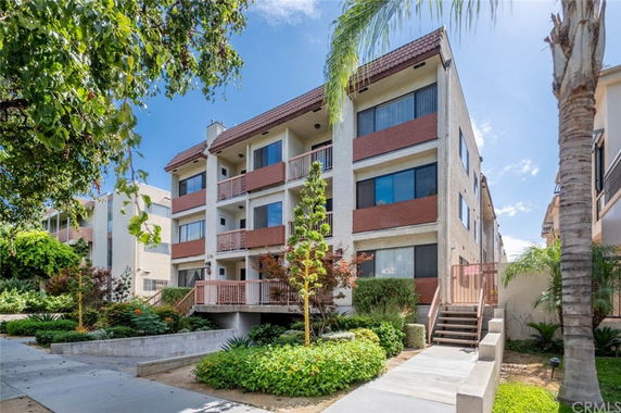 Front view of a multi-story residential building with balconies and a sloped roof.