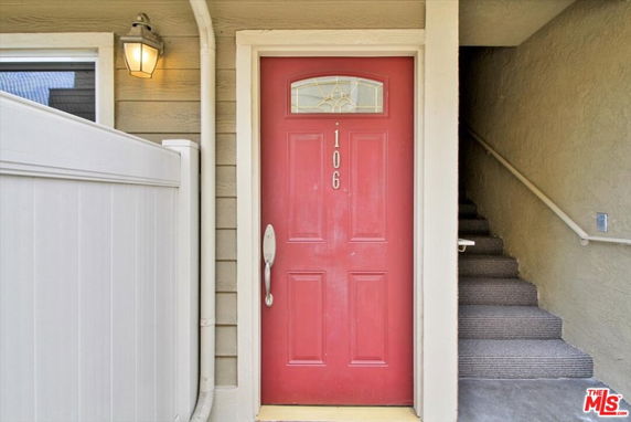 Front view of a building entrance with a red door marked 106 and adjacent stairs.