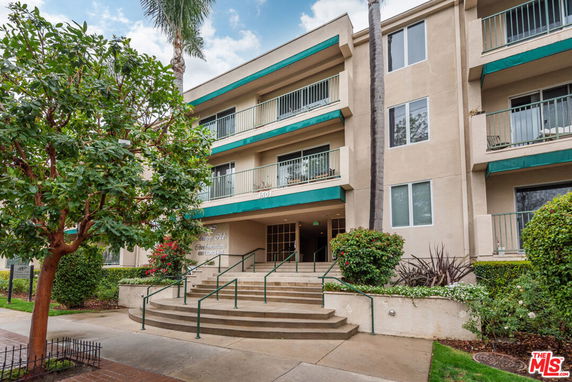 Front view of a three-story apartment building with balconies and a central entrance.