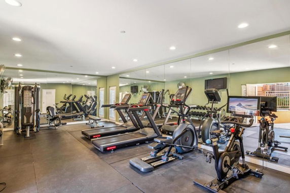 Gym area with treadmills, stationary bikes, and weightlifting equipment.