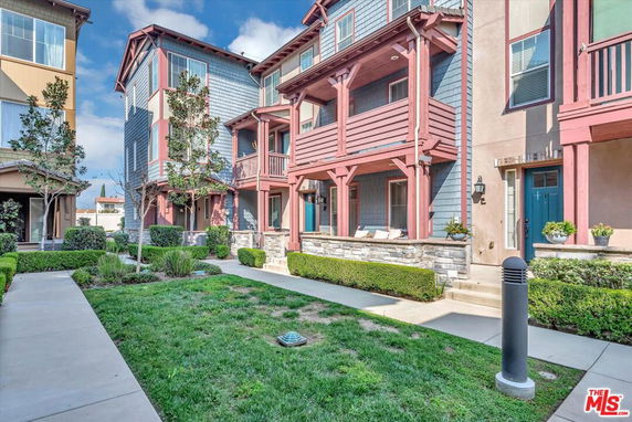 Front view of a multi-story residential building with balconies and a landscaped walkway.
