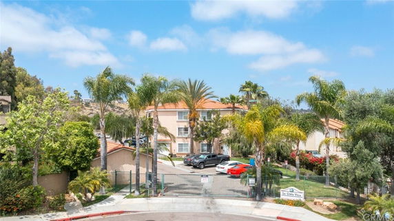 Front view of a multi-story building with a gated entrance and surrounding palm trees.
