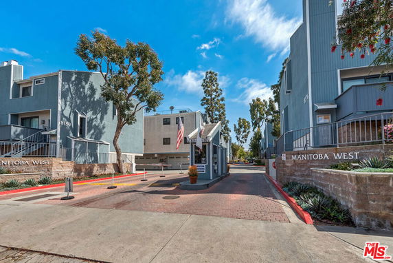 Front view of a residential building complex with an entrance gate labeled Manitoba West.