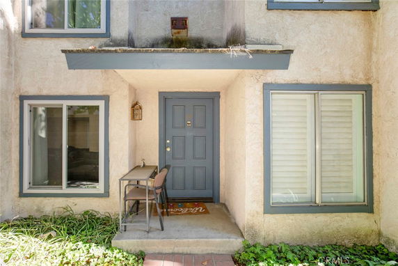Front view of a house entrance with a small porch and two windows.