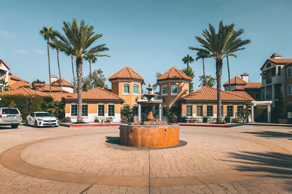 Front view of a residential building with a circular driveway and central fountain.