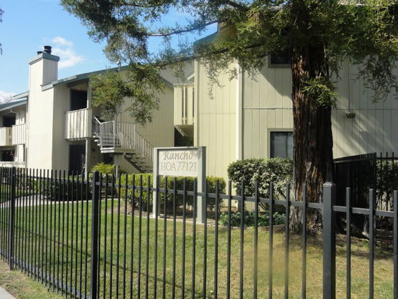 Front view of a two-story apartment building with a fence and exterior staircase.