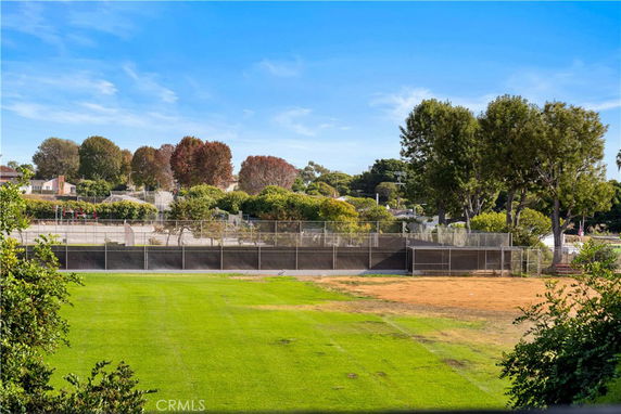 View of a sports field with a grassy area and surrounding trees.