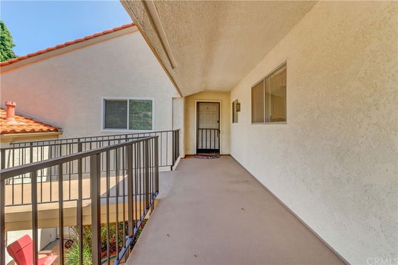 Exterior corridor leading to the entrance of a residential building.