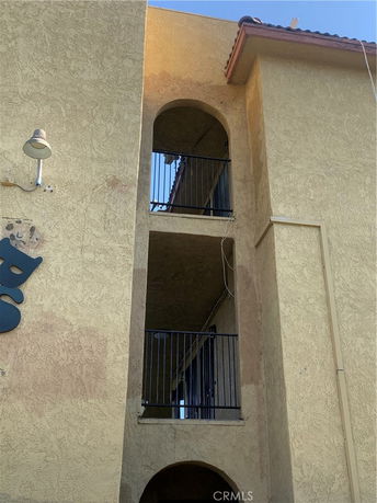 Front view of a multi-story building with balconies and arched openings.