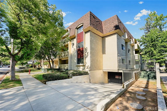 Front view of a multi-story residential building with a sloped roof and gated entrance.