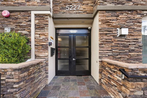 Front entrance of a building with stone facade and glass door.