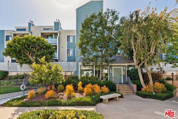 Front view of a multi-story residential building with balconies and landscaped garden.