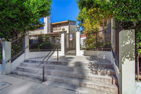 Front view of a multi-story building with a gated entry and stairs.