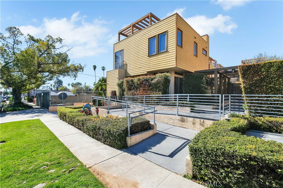 Front view of a modern two-story house with wooden exterior and metal railings.