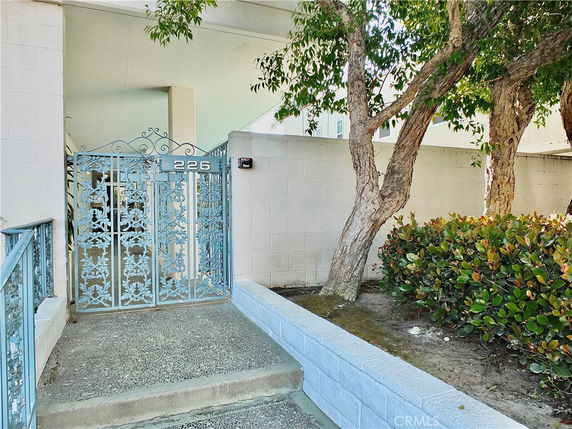 Front view of a gated entrance with a decorative metal gate and adjacent walkway.