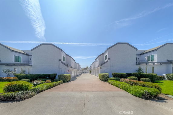 Front view of multiple modern two-story townhouse buildings with a central pathway.