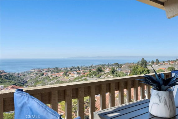 Panoramic view from a balcony overlooking a coastal landscape and distant sea.