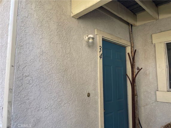 Front view of an outdoor entrance with a blue door and stucco walls.