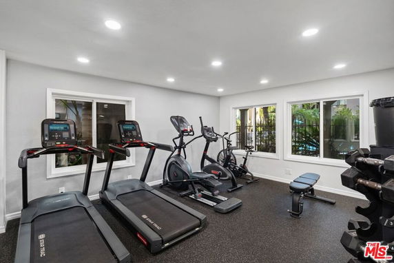 Indoor gym area with exercise equipment including treadmills and weights.