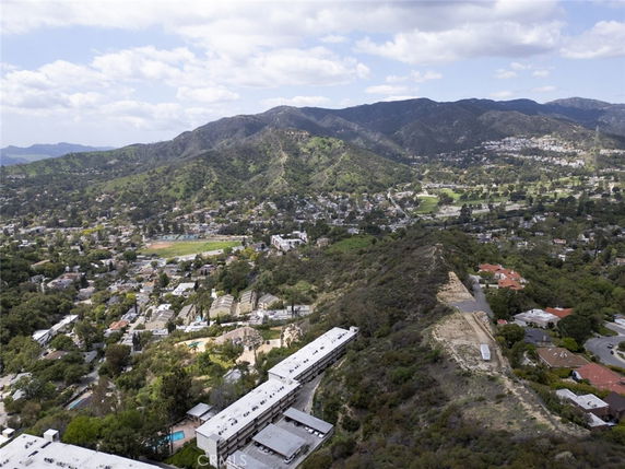 Aerial view of residential area surrounded by hills and greenery.