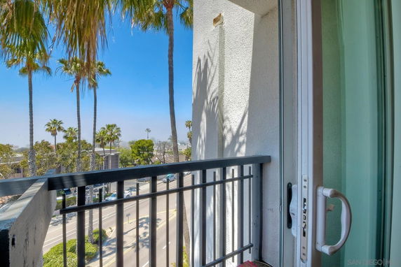 View from a balcony with palm trees and a road visible below.