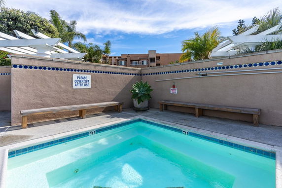 Outdoor swimming pool with a bench and privacy wall.