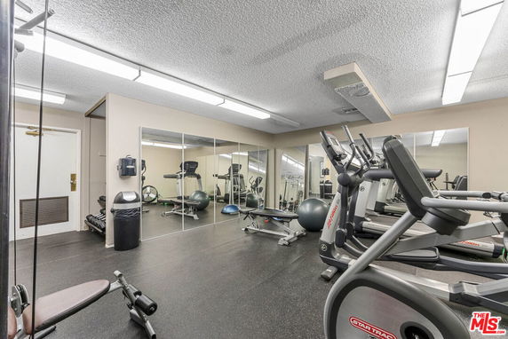 Indoor gym area with exercise equipment including treadmills and weights.