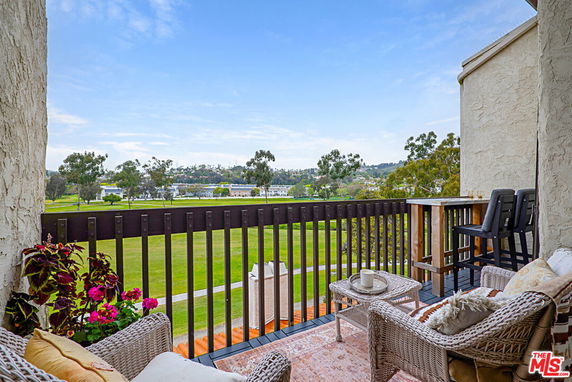 Outdoor balcony with seating, overlooking a park or golf course.
