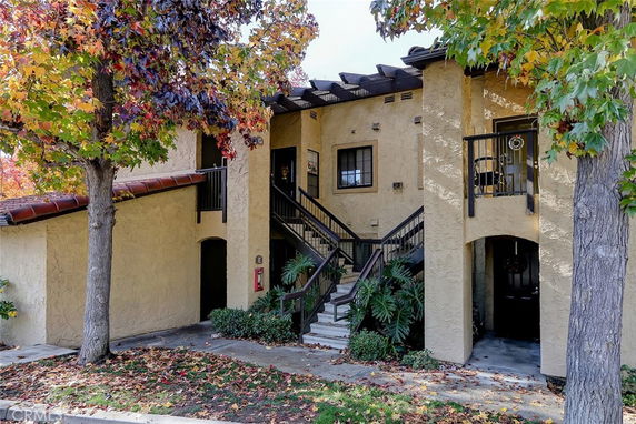 Front view of a building with stairs leading to an upper level and a covered entrance.