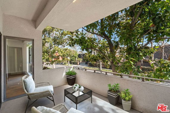 Balcony view featuring outdoor seating and surrounding trees.