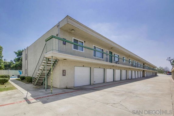 Front view of a multi-story building with garages on the ground level.