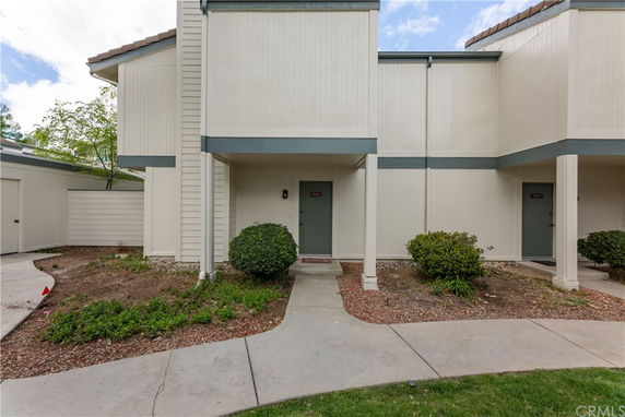 Front view of a multi-story townhouse with a small entrance path and minimal landscaping.