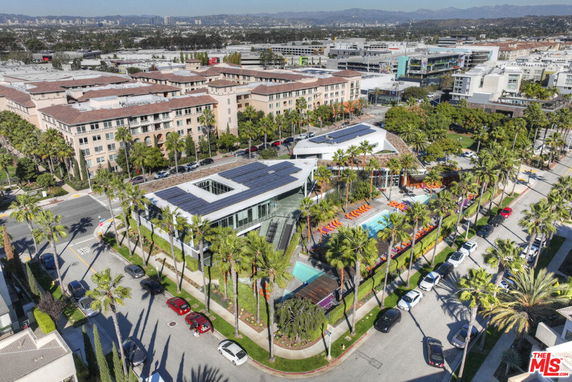 Panoramic view of a building complex with a central swimming pool and surrounding landscape.