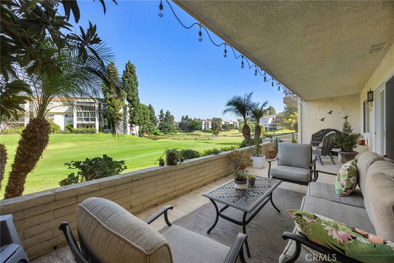Patio area with outdoor seating overlooking a grassy landscape and distant buildings.