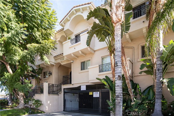 Front view of a multi-story residential building with balconies and a gated entrance.