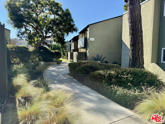 Front view of a multi-story building with a walkway and trees.