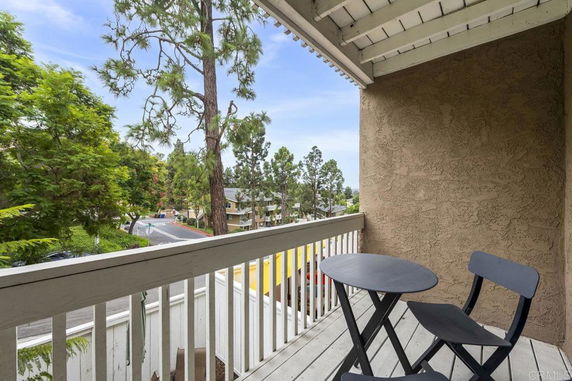 View from a balcony overlooking a street and trees.