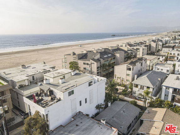 Aerial view of beachfront residential buildings with a wide beach and ocean in the background.