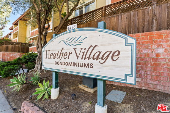 Front view of a condominium building with a sign reading 'Heather Village Condominiums'.