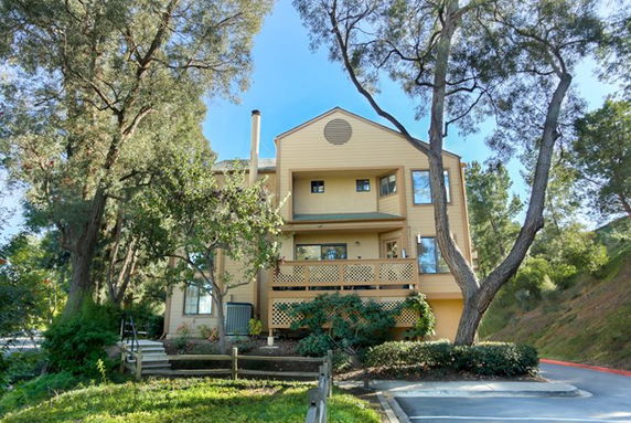 Front view of a multi-story house with trees in front.