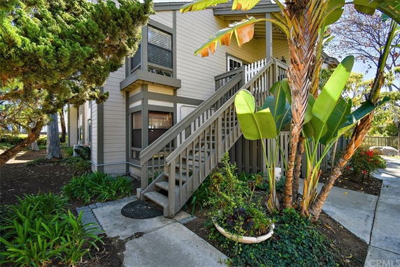 Front view of a wooden house with an external staircase leading to the entrance.
