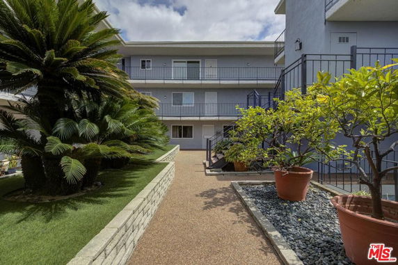 Front view of a multi-story residential building with balconies and landscaped area.