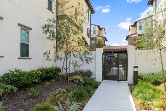 Front view of a multi-story building with a gated entrance and landscaped walkway.