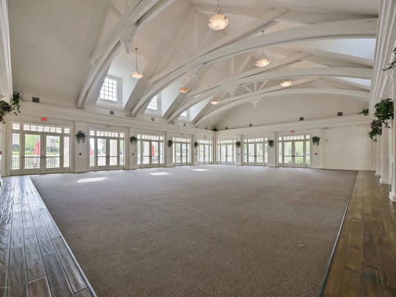 Spacious interior of a club house with high ceilings and large windows.