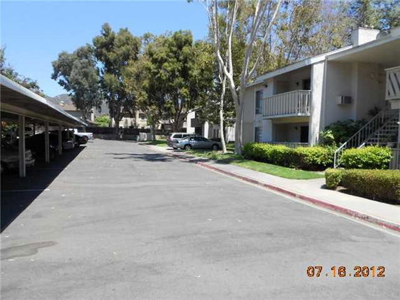 Outdoor parking area beside residential buildings with covered parking spaces.